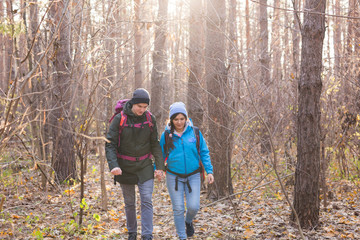 Fototapeta premium adventure, travel, tourism, hike and people concept - smiling couple walking with backpacks over natural background