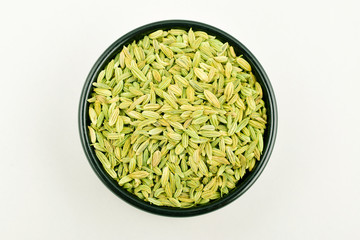fennel seeds top view in black bowl isolated on white background.