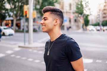 Young fashionable handsome man on the street of modern city. He looks happy and smiling