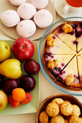 Above view of various tasty dishes such like zephyr, cherry cake, cookies and fresh fruits on party table