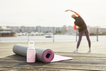 Back view of unrecognizable woman stretching on wooden pier outdoors with focus on yoga mat in foreground, copy space - obrazy, fototapety, plakaty