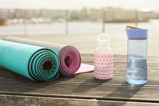 Background image of yoga mats and water bottles set for workout on wooden pier outdoors, copy space