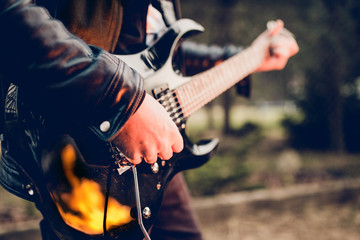 Black electric guitar at night in a bright flame of fire