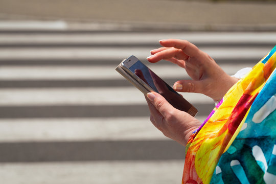 The woman, straring at the phone, crosses the streets / concept