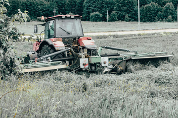 Fototapeta premium Tractor mows the grass. harvesting hay for the winter