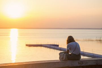 Fototapeta premium girl sitting on the promenade at sunset