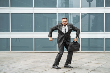 Cheerful business man dancing near the office building on the street