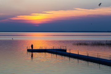 Fototapeta na wymiar men on pontoon pier at sunset