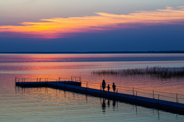 Fototapeta na wymiar family on pontoon pier at sunset