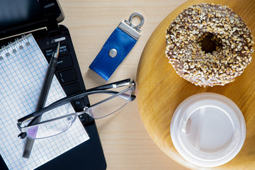 Office table. An open laptop, a notebook with a pen, a cup of coffee on a tray. Wooden table. Top...
