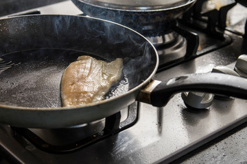 Fresh Fish on frying pan in kitchen, cooking concept.