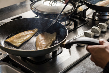 Fresh Fish on frying pan in kitchen, cooking concept.