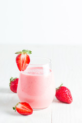 A glass of fresh strawberry smoothie on a wooden background. Summer drink shake, milkshake, juice and refreshment organic concept.