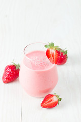 A glass of fresh strawberry smoothie on a wooden background. Summer drink shake, milkshake, juice and refreshment organic concept.