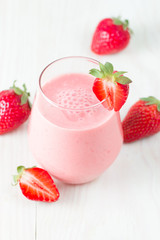 A glass of fresh strawberry smoothie on a wooden background. Summer drink shake, milkshake, juice and refreshment organic concept.