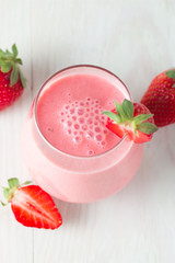 A glass of fresh strawberry smoothie on a wooden background. Summer drink shake, milkshake, juice and refreshment organic concept.