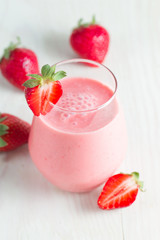A glass of fresh strawberry smoothie on a wooden background. Summer drink shake, milkshake, juice and refreshment organic concept.
