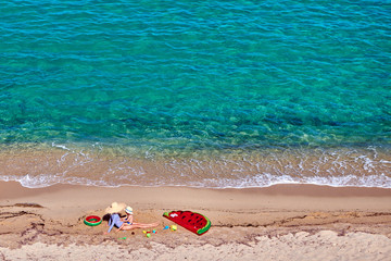 Two year old toddler boy and his mother on beach with inflatable float and ring. Summer family vacation. Sithonia, Greece.