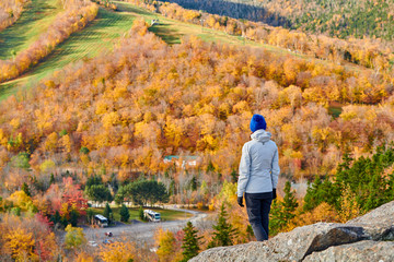 Woman hiking at Artist's Bluff in autumn. Fall colours in Franconia Notch State Park. White Mountain National Forest, New Hampshire, USA