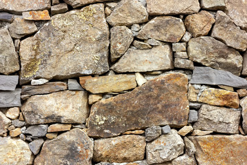 The old wall of natural stone in the mountains, covered with moss.