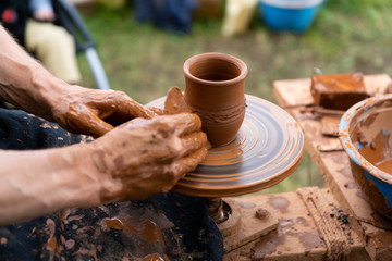 Fototapeta na wymiar hands of potter creating jar on a circle
