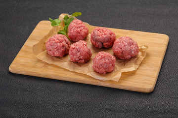 Raw meatball over wooden background
