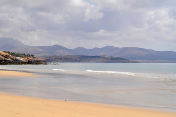 Sandy ocean beach with mountains on background. Costa Calma, Fuerteventura, Canary Islands