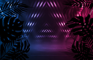 Background of empty dark scenes with neon lights and shapes, smoke. Silhouettes of tropical palm leaves in the foreground. Bright futuristic abstract background