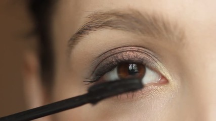 Closeup portrait of woman applying mascara using brush