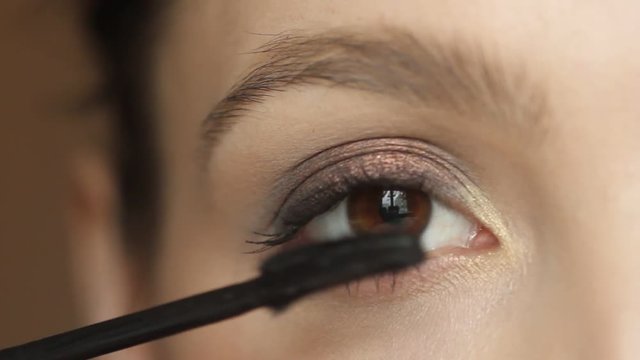 Closeup portrait of  woman applying mascara using  brush