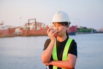 Female engineer wearing a white safety helmet holding a red radio for communication