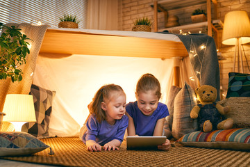 children are playing with tablet in tent