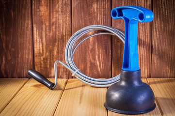 Clean plastic plunger with blue handle and cable on wooden background