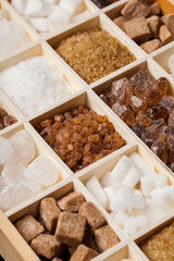 Various kinds of sugar in a wooden box. White refined, brown cane sugar collection