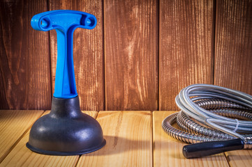Clean plastic plunger with blue handle and cable on wooden background