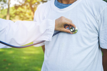 Female doctors use medical stethoscope to check the heart of male patients.