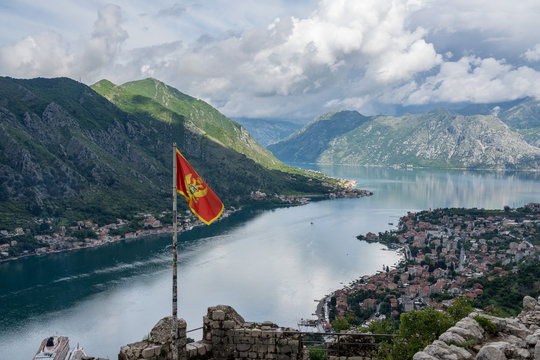 Aerial view of Dobrota and Kotor from hike to Fortress with Montenegro national flag - Powered by Adobe