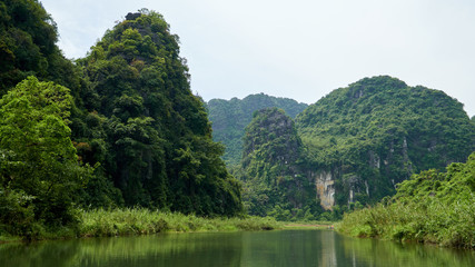 Fototapeta na wymiar Beautiful landscape with river, mountains and tropical forest in Trang An, Tam Coc, Ninh Binh, Vietnam.
