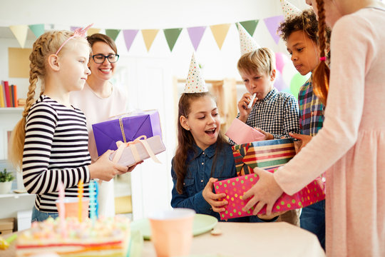 Portrait of happy teenage girl receiving gifts surrounded by friends during Birthday party, copy space