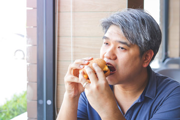 Fat Asian people are eating hamburgers.