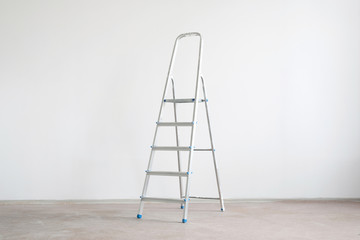 Ladder on a white wall background with copy space. Under construction concept background.