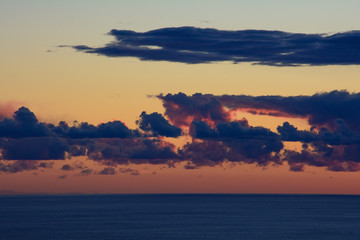 Tramonto sul mare e nubi tinte di rosso