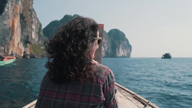 girl rides a boat to the rocks in the ocean