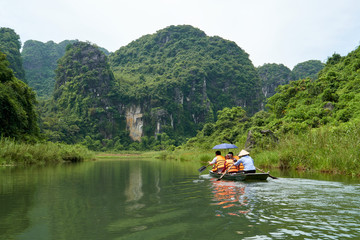 Fototapeta na wymiar Boat with tourists, karst mountains and river, Trang An, Ninh Binh, Tam Coc, Vietnam. 