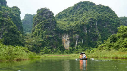 Boat with tourists, karst mountains and river, Trang An, Ninh Binh, Tam Coc, Vietnam. 