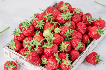 Strawberries in a box on the white concrete background