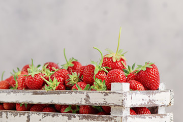 Strawberries in a box close up on the white concrete background