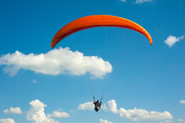 One paraglider is flying in the blue sky against the background of clouds. Paragliding in the sky...