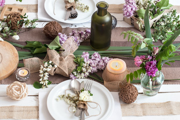 Beautifully elegant decorated table for holiday - wedding or valentine day with modern cutlery, bow, glass, candle and gift