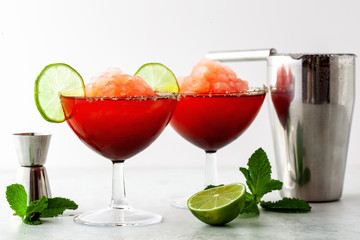 Red Frozen Margarita, refreshing cocktail on the table and lime with mint